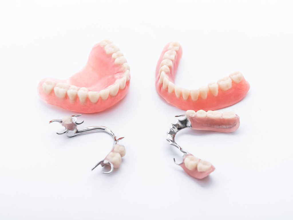 picture of full mouth dentures next to partial dentures