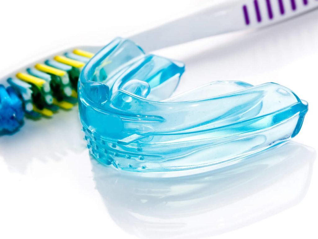 picture of blue mouth guard next to toothbrush