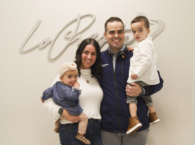 dr matthew lopresti with wife and two kids smiling in office