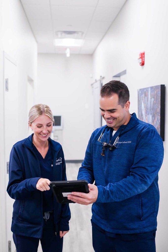 dr showing team member ipad in hallway of office