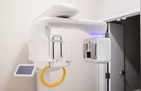 Modern cone beam computed tomography (CBCT) machine used for detailed 3D imaging of a patient's dental structures, consisting of a central column with an arm that holds the X-ray source and detector, rotating around the patient's head.