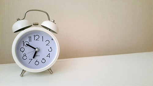 alarm clock sitting on desk representing how long dental veneers last.
