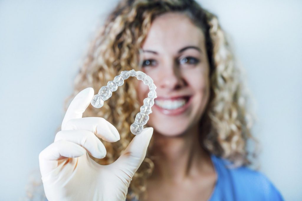 Female dentist holding a transparent dental aligner